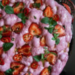 Unbaked sourdough strawberry focaccia in a skillet topped with strawberry and chipotle slices